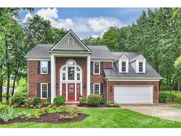 Charming brick two-story home with a red front door, manicured lawn, and lush landscaping at 6722 Elmstone Dr, Charlotte, NC 28277