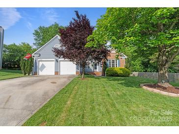 Charming home featuring a well-manicured lawn, mature trees and an attached two-car garage at 1310 Bellhook Nw Pl, Concord, NC 28027