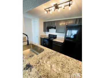 Modern kitchen featuring granite countertops, stainless steel sink, and black appliances at 1624 Arlyn Cir # G, Charlotte, NC 28213