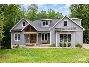 Charming grey two-story home with a wooden door, front porch swing, and a well-manicured lawn at 5215 Star Magnolia Ct, Clover, SC 29710