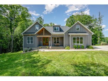 Charming gray farmhouse-style home with a welcoming front porch, lush green lawn, and mature trees at 5215 Star Magnolia Ct, Clover, SC 29710