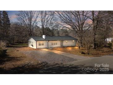 Charming single-story home featuring a white brick exterior, gravel driveway, and a well-manicured front yard at 5520 Chestnut Dr, Hickory, NC 28602