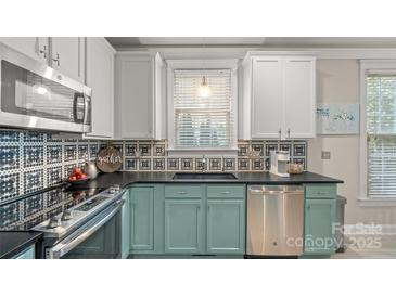 Well-lit kitchen with blue and white cabinets, modern appliances, and a unique backsplash design at 6129 Caseys Side Way, Fort Mill, SC 29708