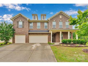 Charming brick home featuring a three car garage, inviting front porch, and well-manicured landscaping at 1355 Cilantro Ct, Fort Mill, SC 29708