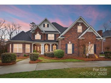 Stunning brick home featuring lush landscaping and a welcoming covered front porch at 201 Limerick Dr, Matthews, NC 28104