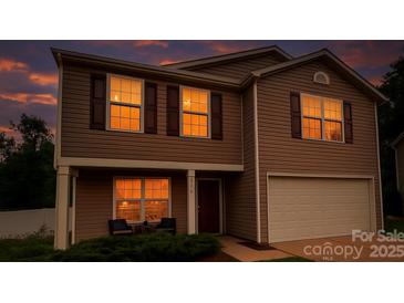Charming two-story home with brown siding, a two car garage, and a cozy front porch with warm lighting at 2021 Tarzi Ln, Charlotte, NC 28215