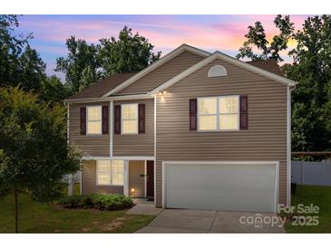 Charming two-story home featuring a two-car garage, complemented by well-maintained landscaping and a beautiful sunset sky at 2021 Tarzi Ln, Charlotte, NC 28215