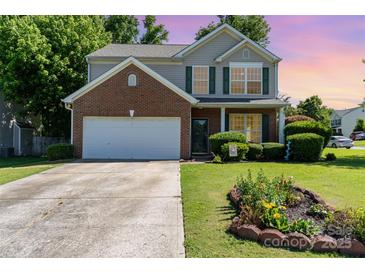 Charming two-story home with a brick accent, green shutters, well-manicured lawn, and a welcoming flower bed at 2206 Waters Trail Dr, Charlotte, NC 28216