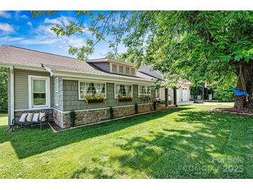 Charming home featuring well-kept lawn, stone accents, flower boxes, and a relaxing bench under a shade tree at 454 N Eastway Dr, Troutman, NC 28166