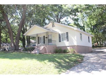 Charming yellow home with a covered front porch and mature trees at 606 E 4Th Ave, Gastonia, NC 28054