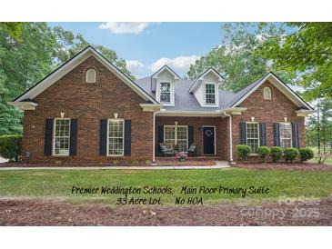 Charming brick home featuring dormer windows, black shutters, mature landscaping, and a welcoming front porch at 105 Prairie Rose Ct, Waxhaw, NC 28173