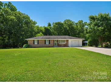 Charming brick home featuring a well-manicured lawn, mature trees, and an attached garage, offering classic curb appeal at 2451 Robert H Kirk Rd, Lancaster, SC 29720
