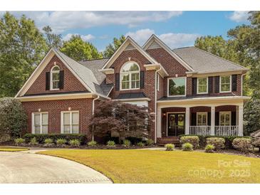 Stately brick home with manicured lawn, mature trees, and a welcoming front porch at 3318 Providence Hills Dr, Matthews, NC 28105