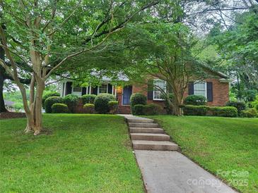 Charming brick home with a well-manicured lawn and mature trees creating a welcoming curb appeal at 6734 Knollgate Dr, Charlotte, NC 28212