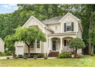 Charming home with a landscaped front yard, covered porch, and inviting curb appeal nestled amongst mature trees at 8256 Chatham Oaks Dr, Concord, NC 28027