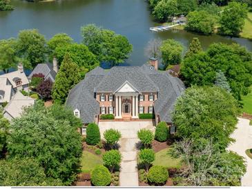 Stunning waterfront estate boasts manicured landscaping and a stately facade with lake views at 8721 Lake Challis Ln, Charlotte, NC 28226