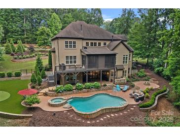 Expansive backyard featuring a pool, spa, outdoor seating, and lush landscaping at 117 Walking Horse Trl, Davidson, NC 28036