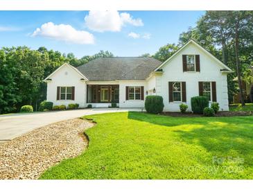 Charming single Gathering home showcasing lush green lawn, complemented by the elegance of white brick and dark shutters at 167 Logan Crossing Dr, Davidson, NC 28036