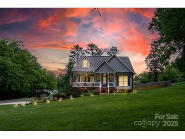 Charming home featuring a landscaped yard, inviting front porch, and patriotic American flag at 240 Hillcrest Dr, Harrisburg, NC 28075