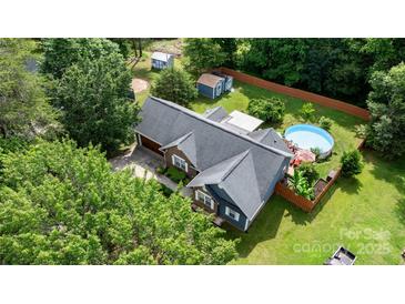 Expansive aerial view of a charming home with a pool, spacious yard, mature trees, and outbuildings at 1305 Creekview Dr, Gastonia, NC 28052