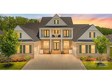 Stunning brick home boasts a two-story entryway with a balcony, lush landscaping, and an expansive driveway at 1702 Batson Creek Ln, Weddington, NC 28104