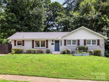 Charming one-story home with a well-maintained lawn, a blue front door and wood shutters at 3530 Woodleaf Rd, Charlotte, NC 28205