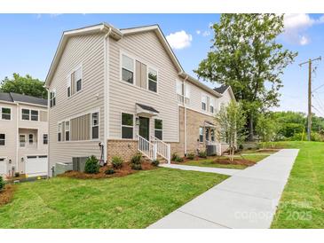 A view of the townhouse featuring manicured lawns, mulched flower beds, and a concrete walkway at 3924 Hager Dr, Charlotte, NC 28208