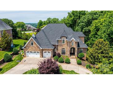 Impressive stone home with a three-car garage, manicured landscaping, and a paver driveway at 4431 1St Street Nw Dr, Hickory, NC 28601