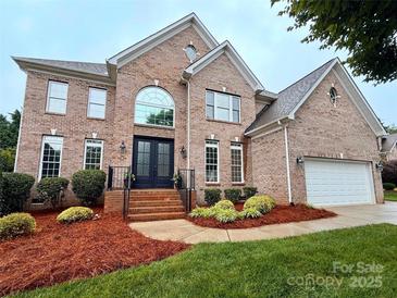 Charming two-story brick home with manicured lawn and black double-door entrance at 8921 Whittingham Dr, Waxhaw, NC 28173