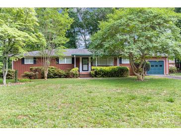 Charming brick home featuring a well-manicured lawn, mature trees, and a cozy one-car garage at 215 Jan Mar Dr, China Grove, NC 28023