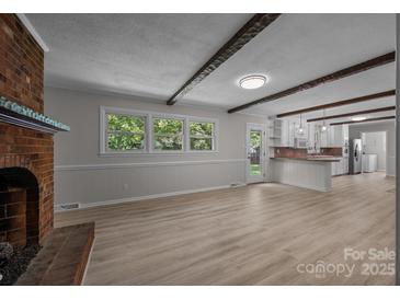 Bright living room with a fireplace, wood floors, beamed ceilings and an open floor plan at 303 Jean Ave, Kannapolis, NC 28083