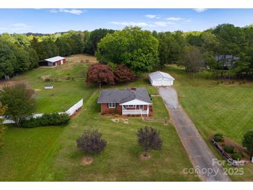 Expansive property featuring a charming brick home with lush landscaping, outbuildings, and a long driveway at 5170 Woodleaf Rd, Salisbury, NC 28147