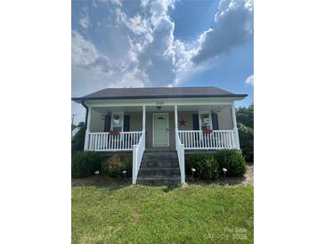 Charming home featuring a welcoming front porch with white railings and meticulously maintained landscaping at 8720 Lee St, Mount Pleasant, NC 28124