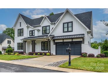 A beautiful two-story home with white siding, black trim, a gray garage door, and a well-manicured lawn at 9426 Greyson Ridge Dr, Charlotte, NC 28277