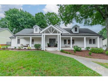 Charming white brick home boasts a covered front porch, dormer windows, and mature landscaping at 1121 S Wendover Rd, Charlotte, NC 28211