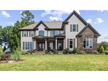 Beautiful two-story home with a manicured lawn, stone accents, and decorative shutters at 18745 Bluff Point Rd, Cornelius, NC 28031