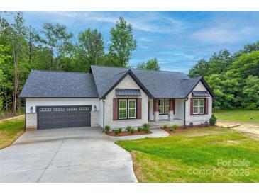 Charming single-story home with a gray roof, brick accents, and an attached two-car garage at 501 Old Speedway Nw Dr # 1, Concord, NC 28027