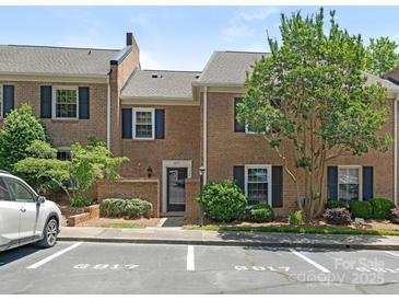 Charming brick townhouse with dark shutters, landscaping, and reserved parking spaces out front at 6817 Dumbarton Dr, Charlotte, NC 28210