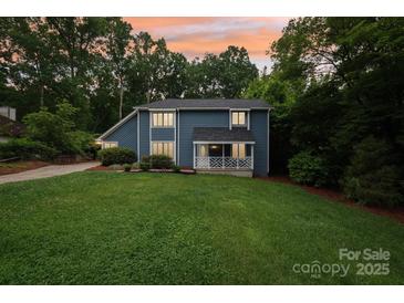Charming blue two-story home featuring a cozy front porch and lush green lawn at 8338 Rittenhouse Cir, Charlotte, NC 28270