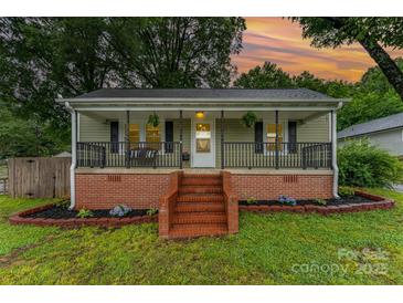 Charming single-story home featuring a welcoming front porch with decorative railings and manicured landscaping at 910 W A St, Kannapolis, NC 28081