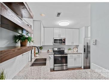 Charming kitchen features white cabinets, stainless steel appliances, granite countertops, and wood floating shelves at 3308 Selwyn Farms Ln # 5, Charlotte, NC 28209
