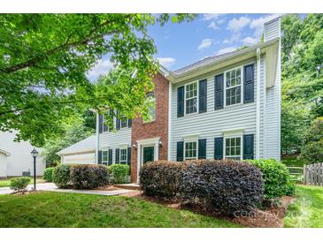Charming two-story home with landscaped yard, brick accent, black shutters, and vibrant green foliage at 6033 Edinmeadow Ln, Charlotte, NC 28269
