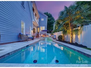 Beautiful backyard pool at dusk featuring a seating area, mature palm trees, and privacy fence at 628 Bracket St, Fort Mill, SC 29708