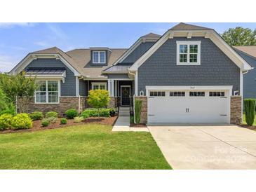 Charming home featuring a manicured lawn, stone accents, gray siding, and an attached two-car garage at 1467 Tranquility Blvd, Lancaster, SC 29720
