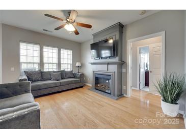 Cozy living room features a fireplace with TV, ceiling fan, and hardwood floors at 14979 Santa Lucia Dr # 2408, Charlotte, NC 28277
