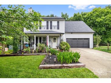 Charming two-story home with manicured lawn and a welcoming front porch and gray siding and black shutters at 4236 Carrington Sw Ct, Concord, NC 28027