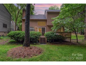 Backyard view showcasing the home's exterior, a spacious deck, and lush green lawn with mature trees at 8968 St Croix Ln, Charlotte, NC 28277