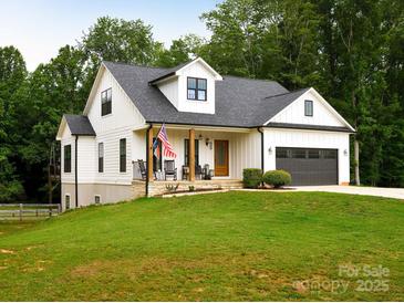 Charming white farmhouse with a cozy front porch and well-manicured lawn at 943 Shinnville Rd, Mooresville, NC 28115