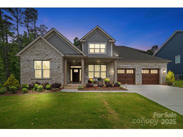 Charming brick home showcasing a manicured lawn and a welcoming three-car garage, blending style and functionality at 9833 Ardley Park Way, Mint Hill, NC 28227