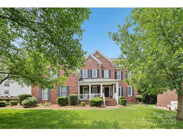 Charming two-story red brick home with a covered front porch and well-manicured lawn and mature trees at 11103 Fountaingrove Dr, Charlotte, NC 28262